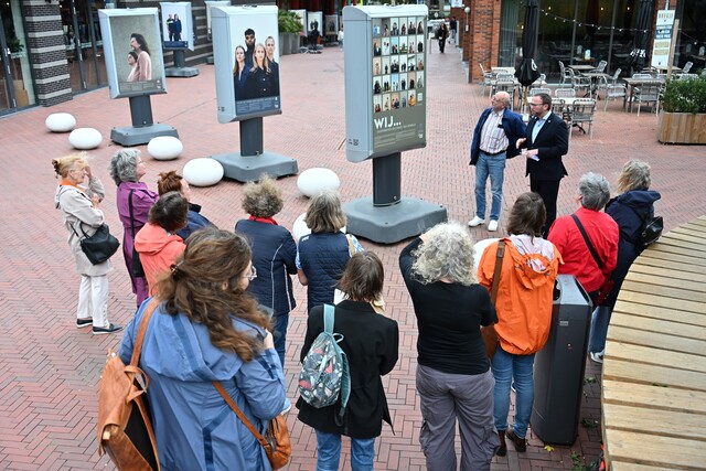 Een groep bezoekers kijkt naar drie panelen uit de expositie WIJ....doorbreken de cirkel van geweld