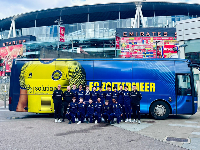 Het eerste elftal van FC Zoetermeer voor hun spelersbus