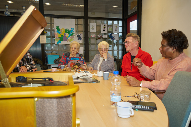 Een groep mensen aan een tafel bij de Plaat & Praat Muziekochtend
