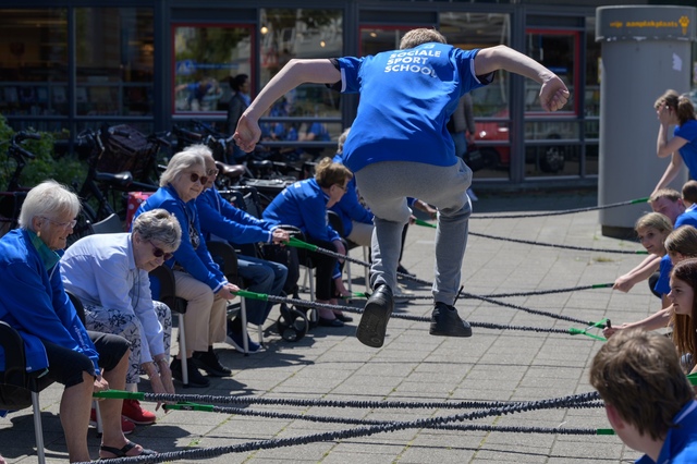 Sporters en ouderen doen samen een oefening bij de sociale sportschool